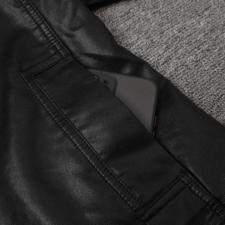 Close-up of a women's belted leather jacket with pockets showing a smartphone tucked inside
