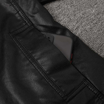 Close-up of a women's belted leather jacket with pockets showing a smartphone tucked inside