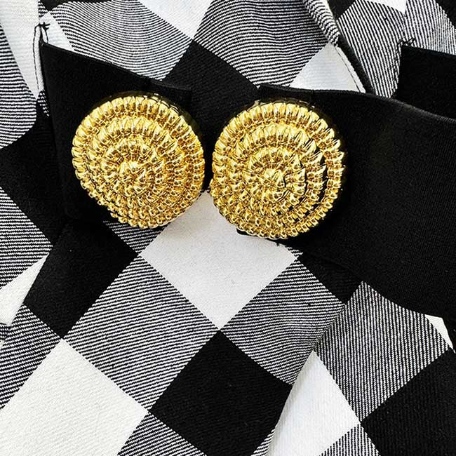 Close-up of women's black checked blazer coat featuring ornate gold buttons for stylish detailing