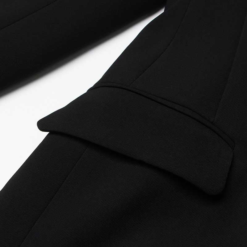 Close-up of a women's black maxi blazer coat showing detailed stitching and pocket design