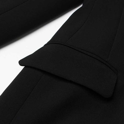 Close-up of a women's black maxi blazer coat showing detailed stitching and pocket design