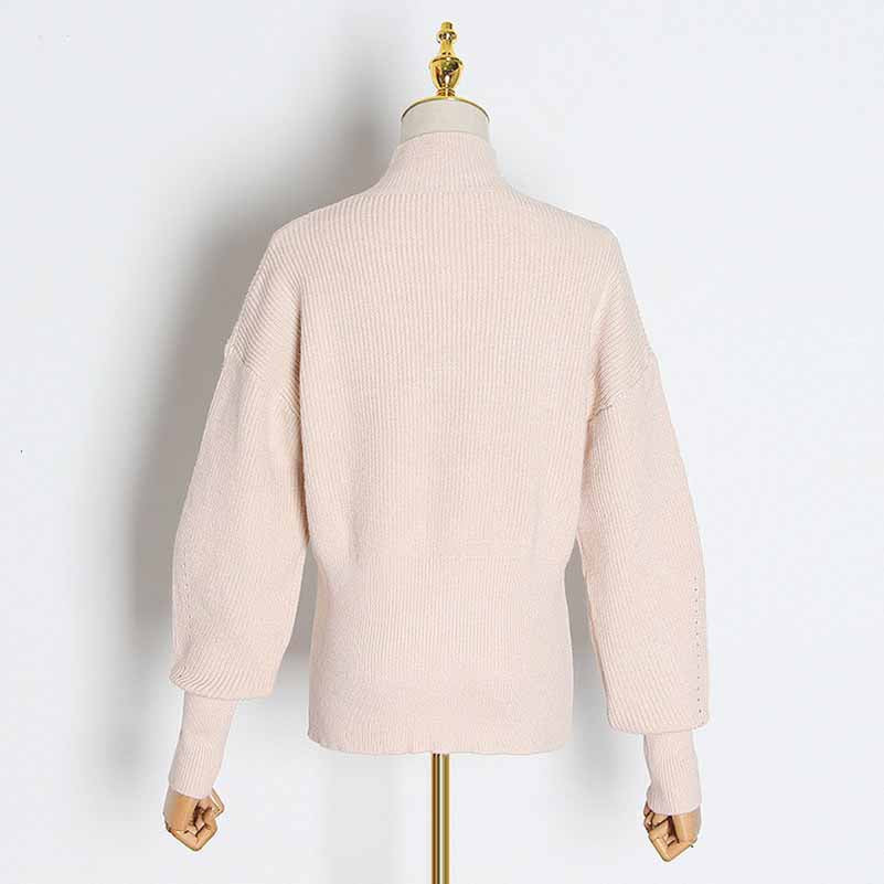 Back view of a women's bow detail sweater in soft pink with relaxed sleeves and ribbed texture