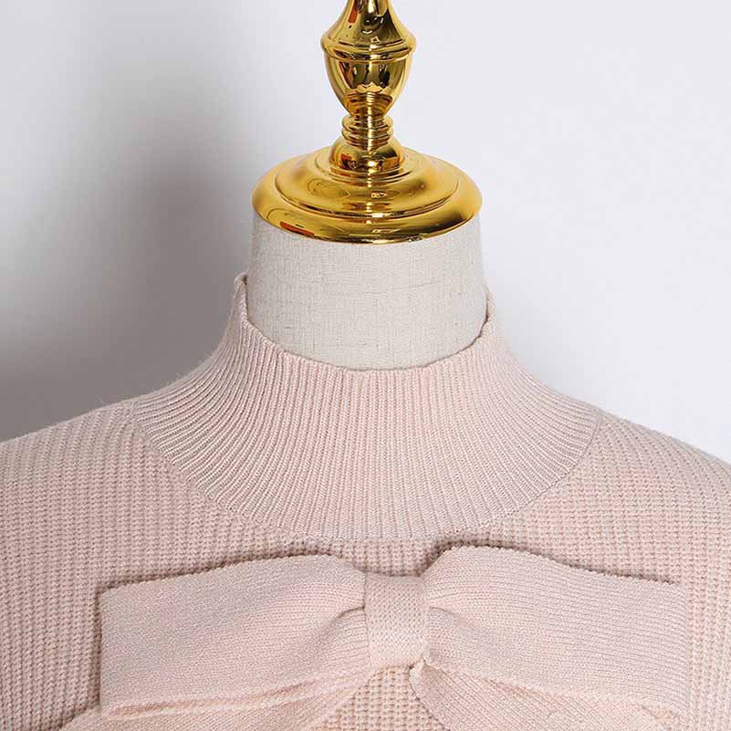Close-up of a women's bow detail sweater with a soft pink hue and textured knit pattern