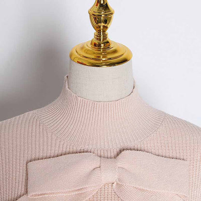 Close-up of a women's bow detail sweater with a soft pink hue and textured knit pattern