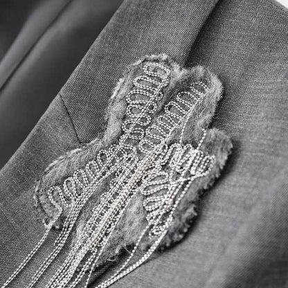 Women's grey tailored pantsuit featuring a stylish embellishment on the blazer