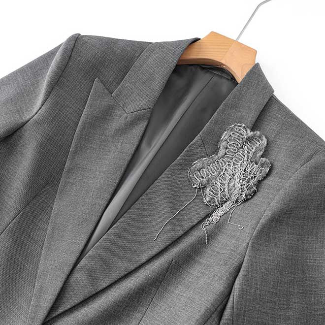 Close-up of women's grey tailored pantsuit featuring a stylish design and intricate embellishment