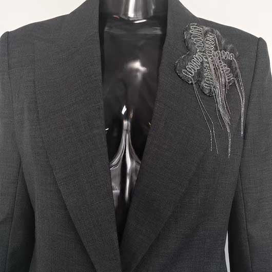 Close-up of SD Dresscode women's grey tailored pantsuit with stylish floral detail on lapel