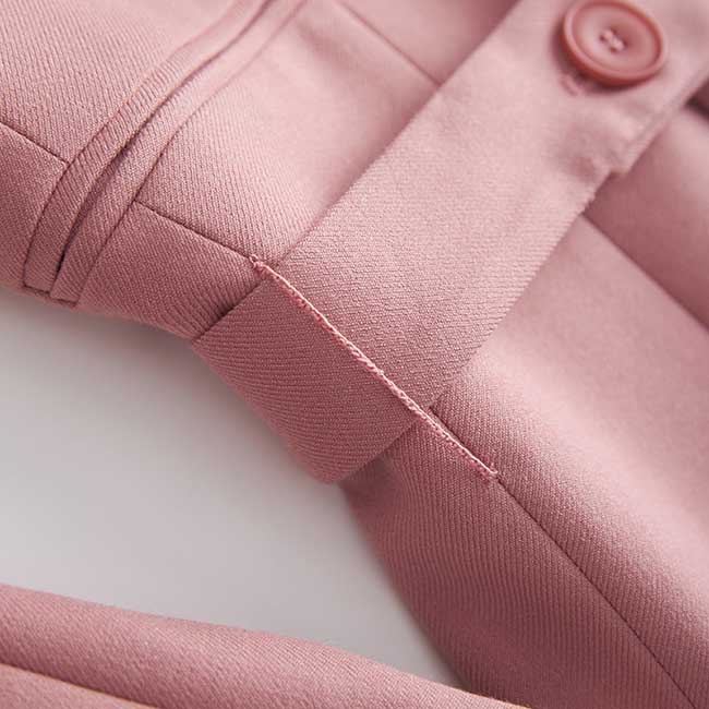Close-up of women's pink pantsuit for formal events showing button and fabric texture