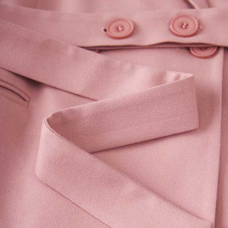 Close-up of women's pink pantsuit for formal events showcasing fabric texture and button details