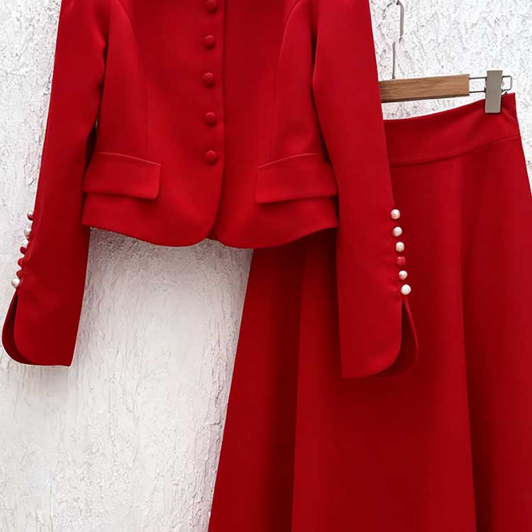 Red women's two piece skirt suit featuring a buttoned blazer and a flowing skirt