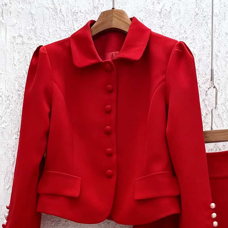 Red women's two piece skirt suit featuring a tailored jacket with button details and elegant finish