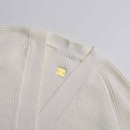 Women's v neck knitted cardigan in cream color featuring ribbed texture and stylish gold logo detail
