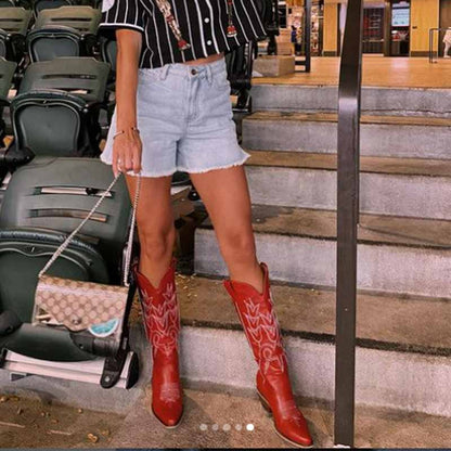 Stylish women's western embroidered boots in red worn with denim shorts and a striped shirt