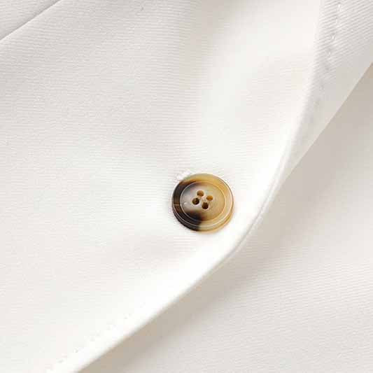 Close-up of a button on a women's white pantsuit set with a sophisticated design