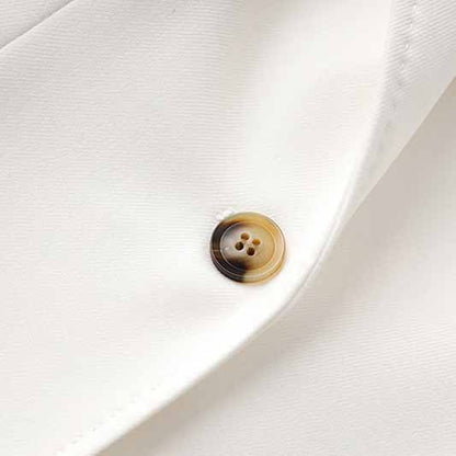 Close-up of a button on a women's white pantsuit set with a sophisticated design