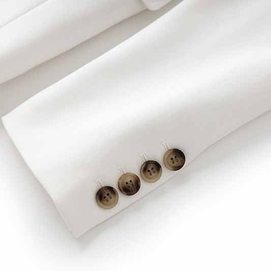 Close-up of women's white pantsuit set with detailed button accents on the sleeves