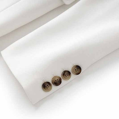 Close-up of women's white pantsuit set with detailed button accents on the sleeves