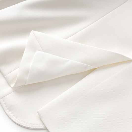 Detail view of the fabric in a women's white pantsuit set showcasing smooth texture and elegant design