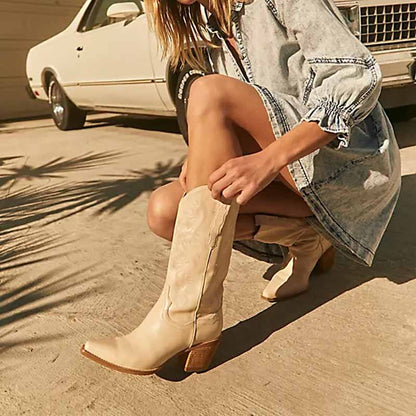 Ivory embroidered cowgirl boots wedding with a stylish heel worn with a denim dress in outdoor setting