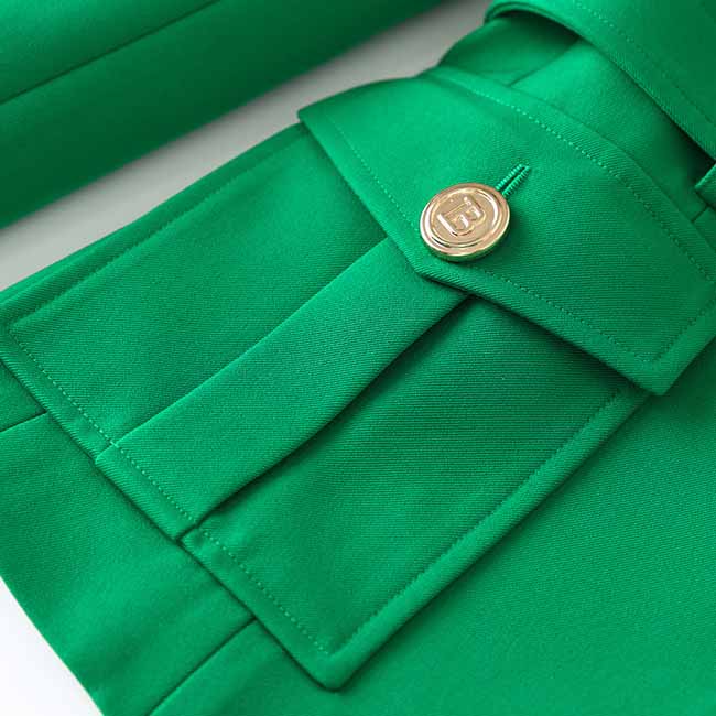 Close-up of an emerald green blazer for women with gold button and tailored pockets