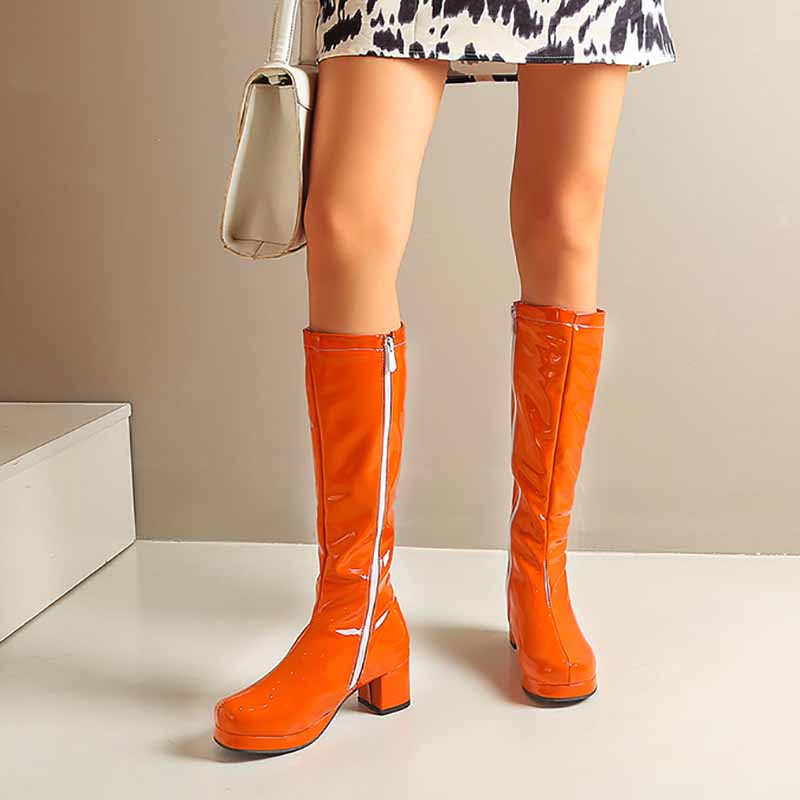 Bright orange fashion boots with zipper for women, styled with a trendy dress and handbag