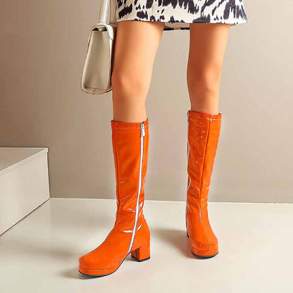 Bright orange fashion boots with zipper for women, styled with a trendy dress and handbag