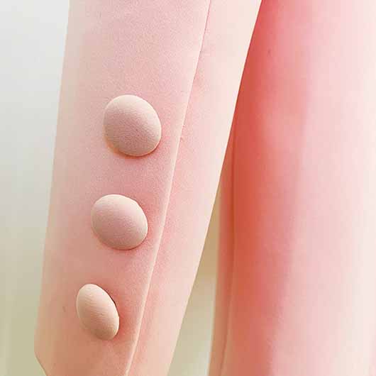 Detail of a pink blazer pantsuit for women showcasing button accents on the sleeve