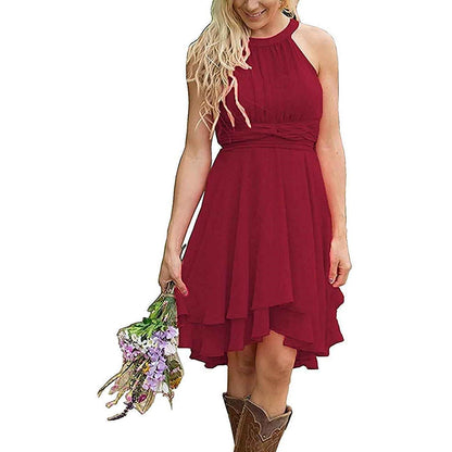 A woman in a burgundy cowgirl bridesmaid dress for rustic wedding, holding flowers outdoors