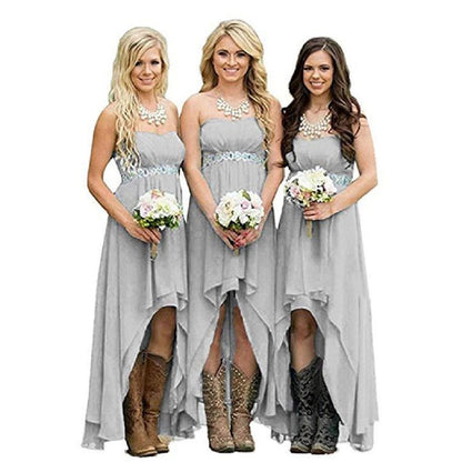 Three bridesmaids in strapless country wedding dress with flowing skirts and cowboy boots, holding floral bouquets