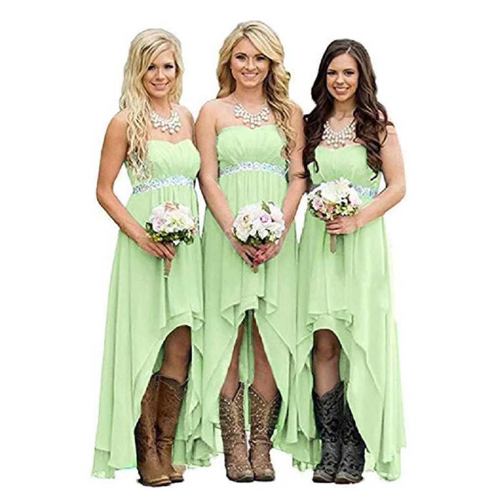 Three bridesmaids wearing strapless country wedding dress in light green with cowboy boots and floral bouquets