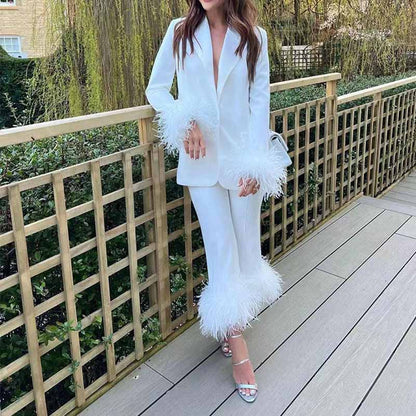 Stylish women's wedding suit with feathers featuring a white blazer and tailored pants for elegant bridal looks