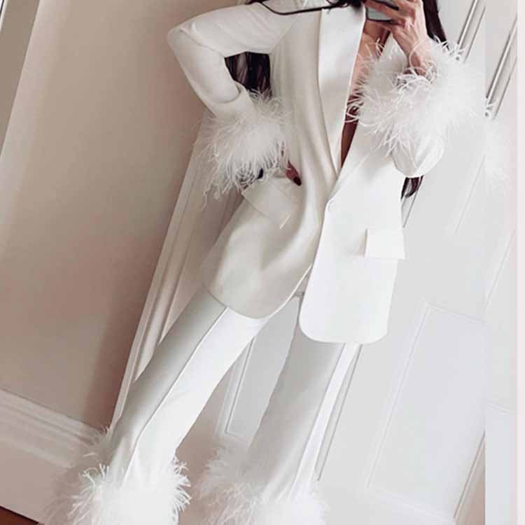 Elegant women's wedding suit with feathers in white featuring chic feather detailing on sleeves and pants