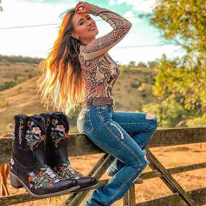 Vintage flower embroidered cowgirl boots displayed next to a model in a rustic outdoor setting