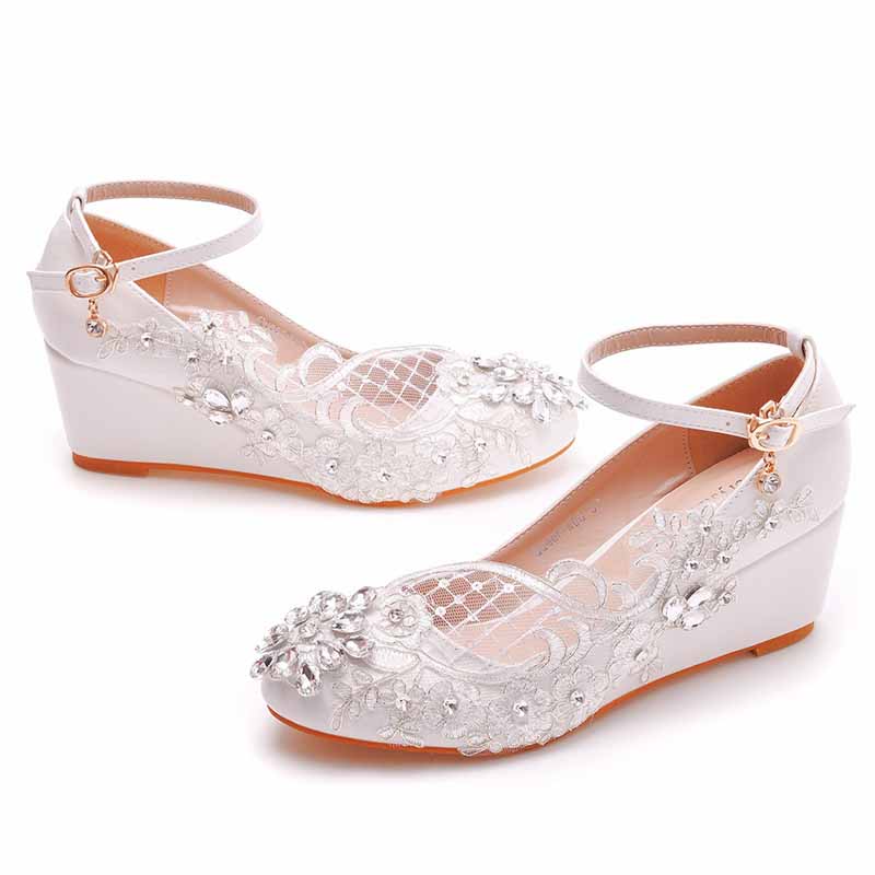 Elegant white wedge bridal sandals with floral embellishments and ankle strap for wedding elegance