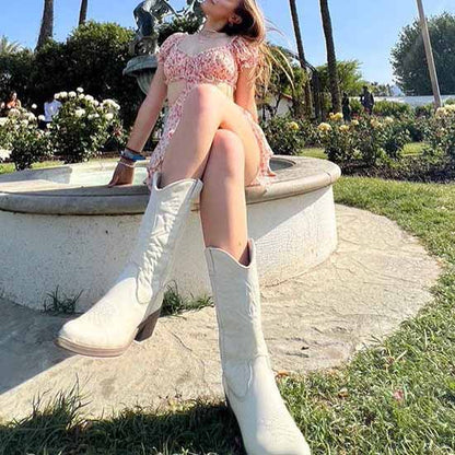 Stylish women's embroidered cowboy boots paired with a floral dress, perfect for outdoor events