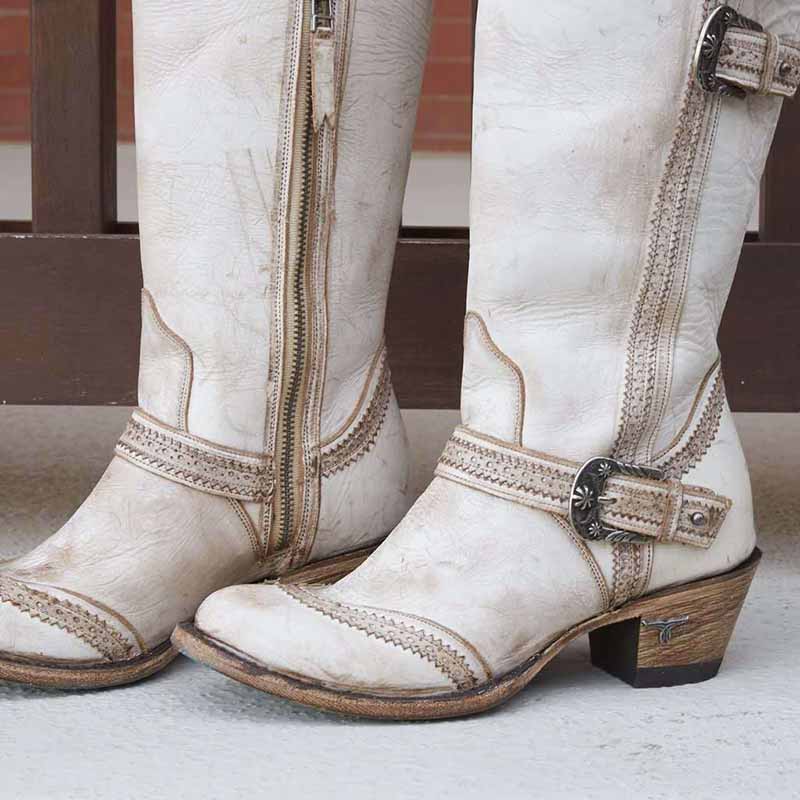 Stylish white women's country cowboy boots with decorative stitching and side zipper in a rustic setting