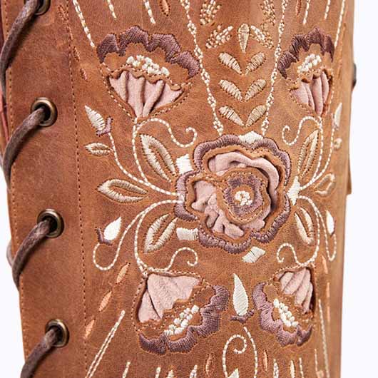 Close-up of women's western knee high boots featuring intricate floral embroidery and laced design