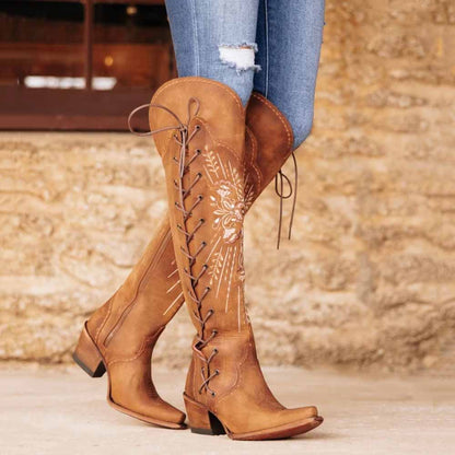 Stylish women's western knee high boots with floral embroidery and lace-up detail.